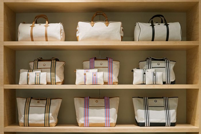 A built-in maple wall at Boon the Shop merchandising weekender duffels, striped totes, and matching pouches across three shelves.