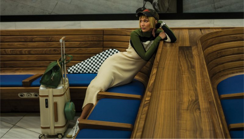 Bella Hadid reclining beside a Paravel Aviator suitcase in an editorial shoot