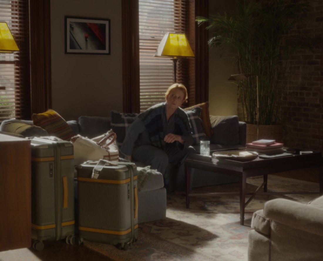 A still from And Just Like That: a character carrying a Paravel weekender in an apartment interior.