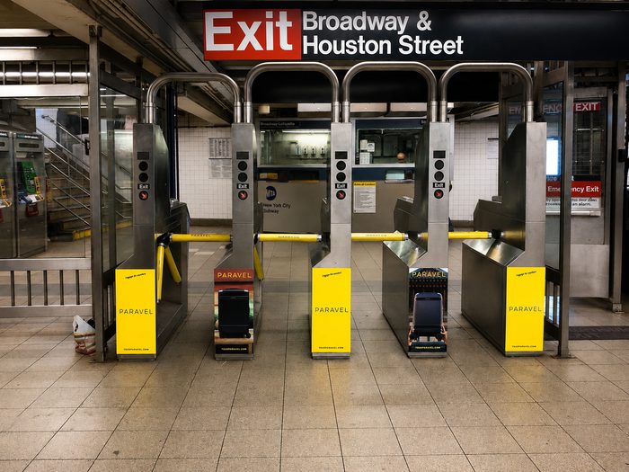 The fare-gate line at Broadway-Lafayette wrapped in yellow PARAVEL panels, beneath the Exit — Broadway & Houston Street sign.